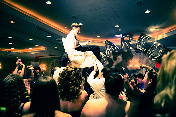 Bar Mitzvah celebration. Brother of the Bar Mitzvah boy is held up on a chair. It is traditional for the child and his family to be raised on chairs during the party.